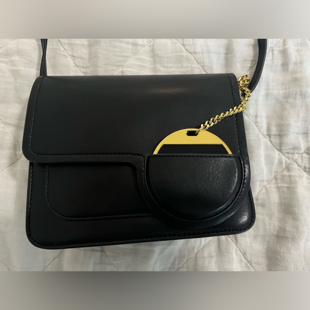 Black JW PEI crossbody bag with a gold chain and mirror attached.